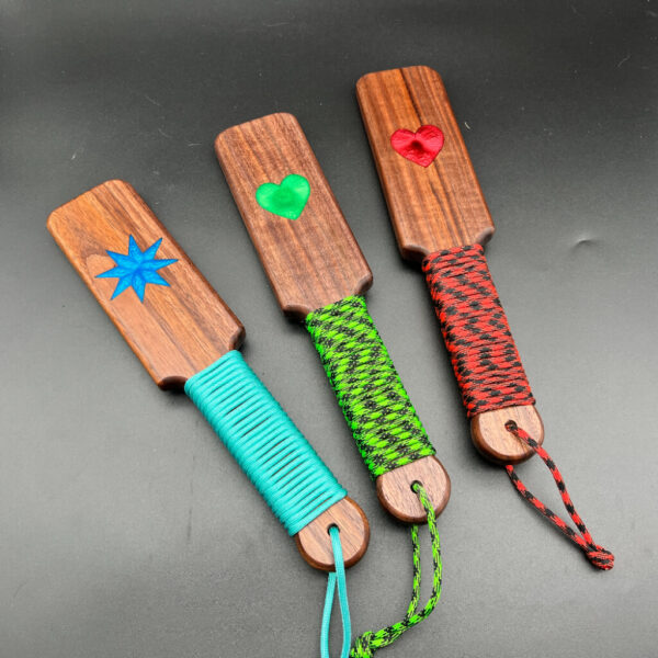 A variety of resin inlay paddles in Black Walnut, from left to right - blue 8-point star, green heart, and red heart