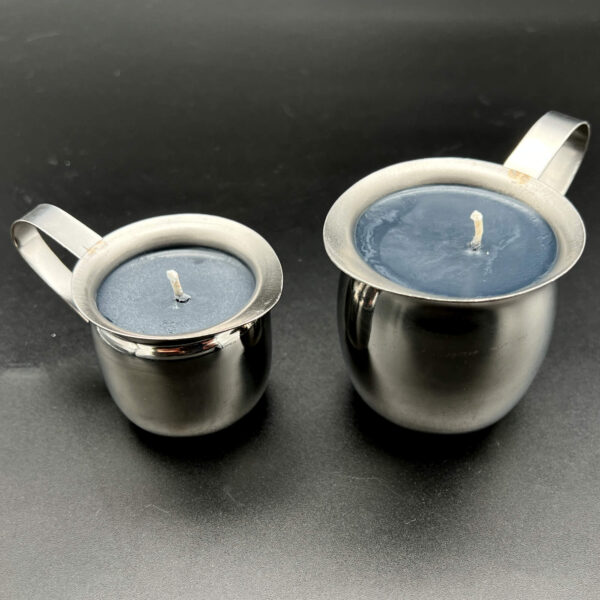 Two black soy wax play candles. On the left, the small (3oz) and on the right, the large (5 oz). Both are silver containers with handles