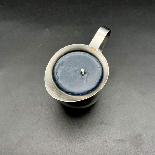 Overhead view of single black soy wax play candle in silver container with handle