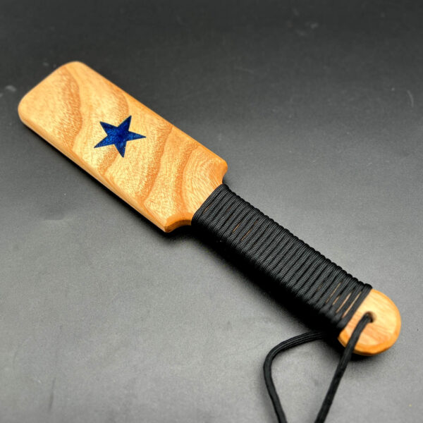 Small wooden paddle made of Ash with blue resin star in the center and black paracord around the handle