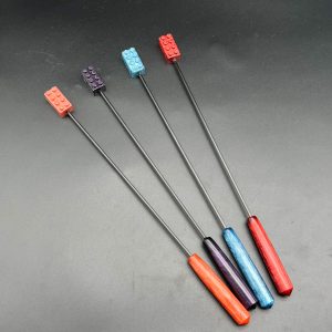 Four building brick diabolical sticks. Left to right: rose gold, purple, blue, red