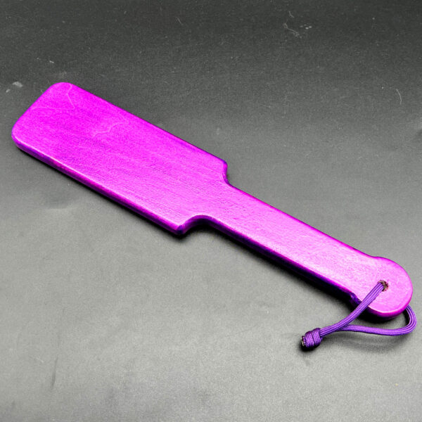 Small wooden paddle stained with purple sparkle unicorn spit