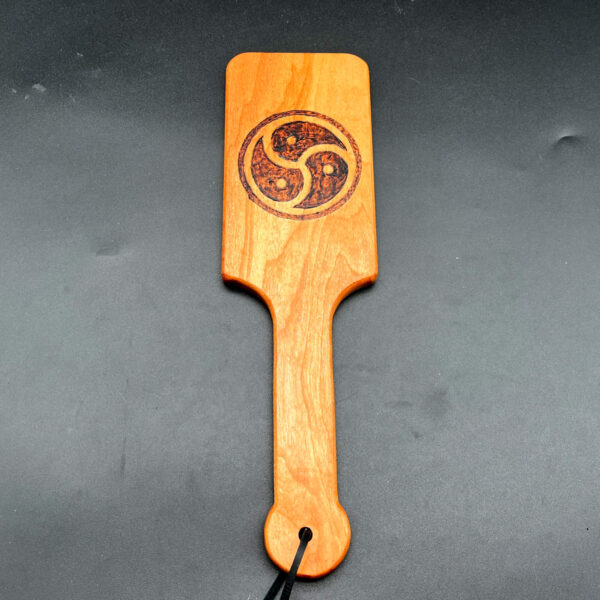 Hairbrush style paddle made of cherry with BDSM triskelion wood burned into the center