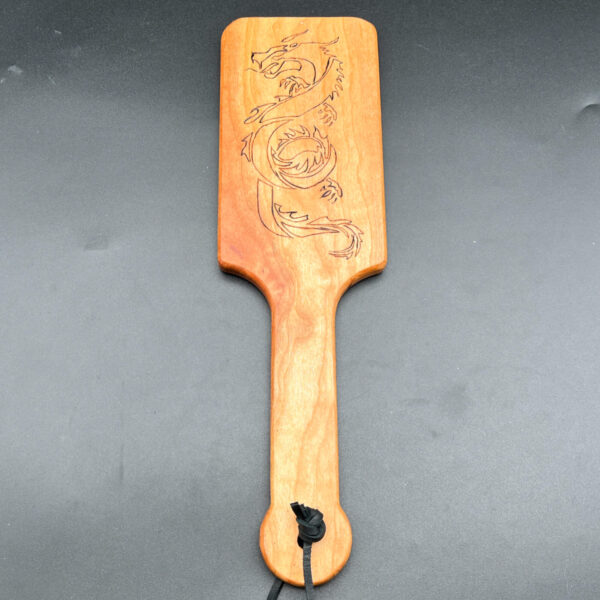 Hairbrush style paddle made of cherry with a wood-burned dragon on the paddle