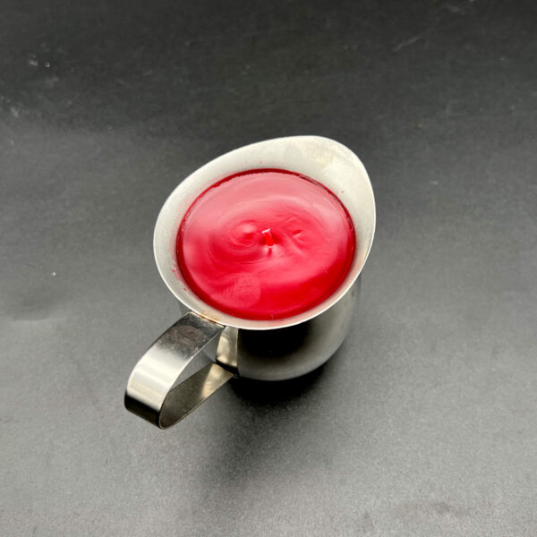 Overhead view of single red paraffin wax play candle in silver container with handle