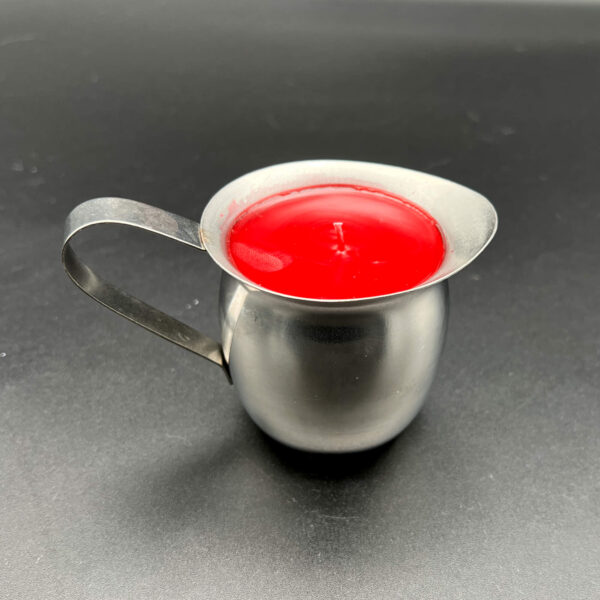 Side view of single red paraffin wax play candle in silver container with handle