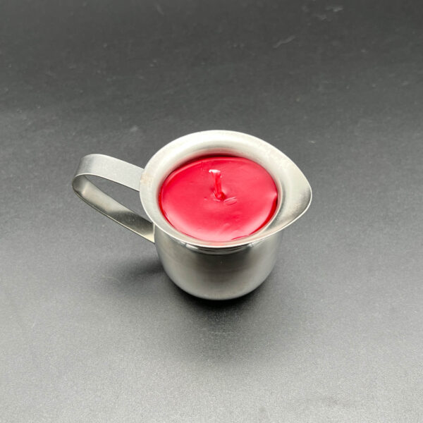 Overhead view of single red paraffin wax play candle in silver container with handle