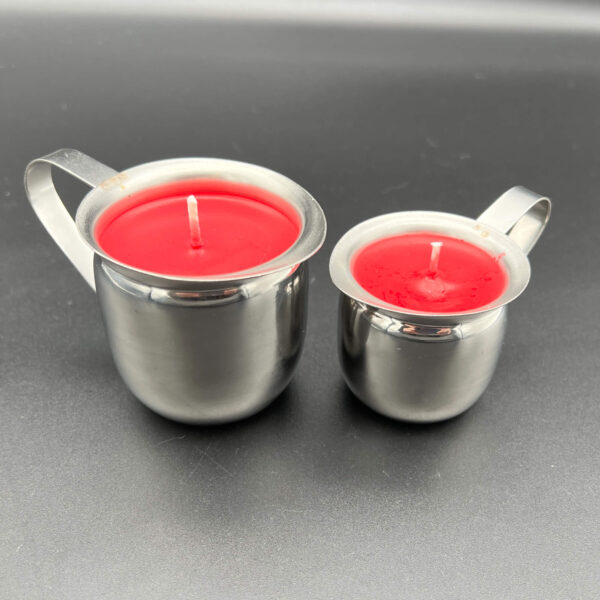 Two red soy wax play candles. On the left, the large (5oz) and on the right the small (3oz). Both are in silver containers with handles