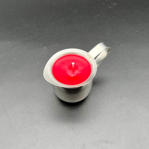 Overhead view of single red soy wax play candle in silver container with handle