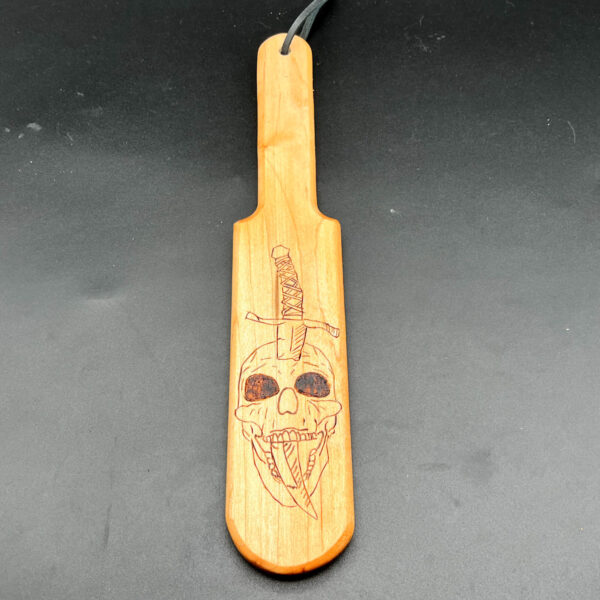 Pounder style paddle made of maple with skull and sword wood burned into center of paddle