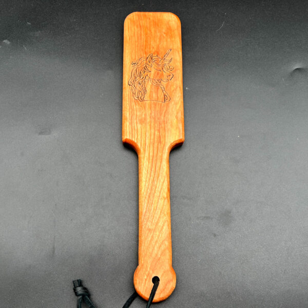Small wooden paddle made of birch wood with unicorn wood-burned into center