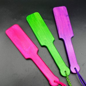 Three wooden paddles stained with a glittery stain. From left to right: pink, green, purple