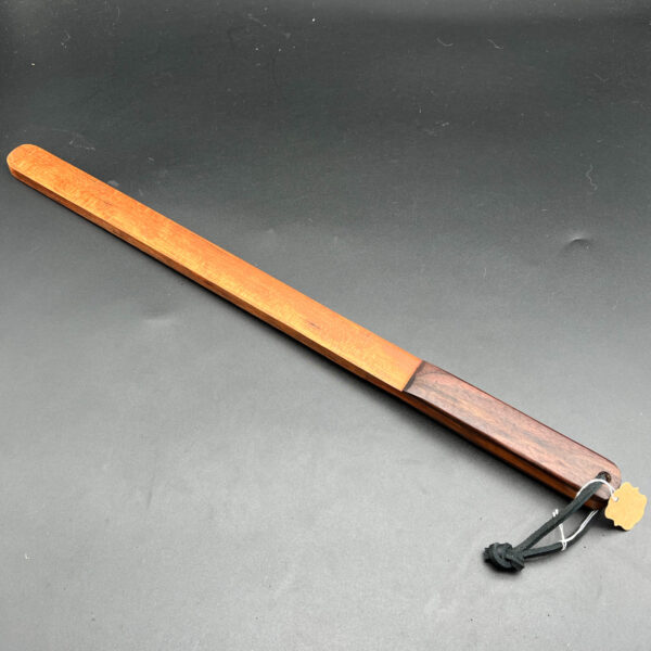 Long narrow wooden thick stick made with cherry wood, an orange-brown color with a laminated handle using black walnut
