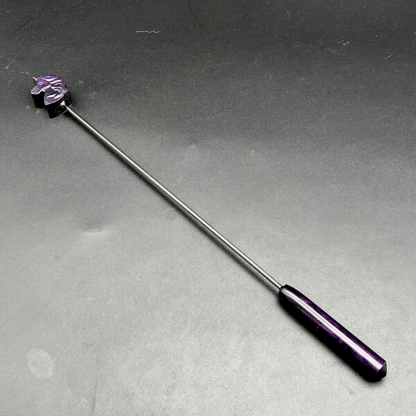 Diabolical stick in purple. On one end is a purple resin unicorn head with a black carbon fiber rod attaching the tip and the handle which is also purple resin. The total length is 13 inches. The tip is about 1 inch long and the handle is about 4 inches long.