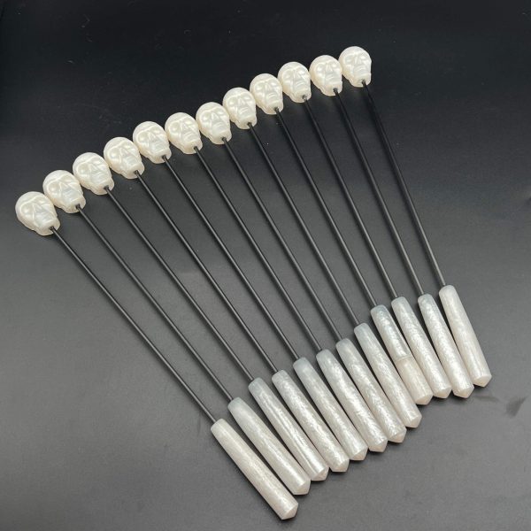 12 skull diabolical sticks in a row - made with white metallic resin and carbon fiber rod.