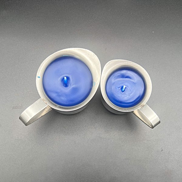 Top down view of blue paraffin wax play candles in 5 ounce (left) and 3 ounce (right) stainless steel containers with pour spouts and handles