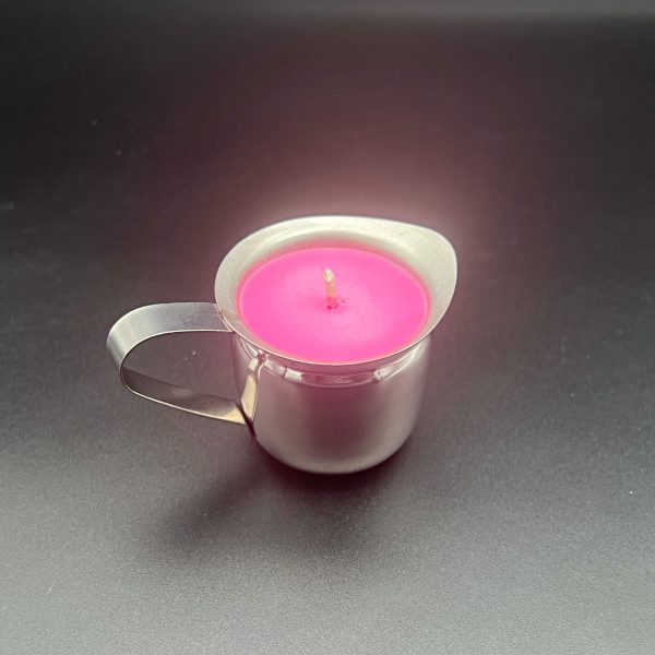 Small stainless steel 3 ounce container - bell creamer - with a handle and pour spout. It is filled with a bright pink soy wax