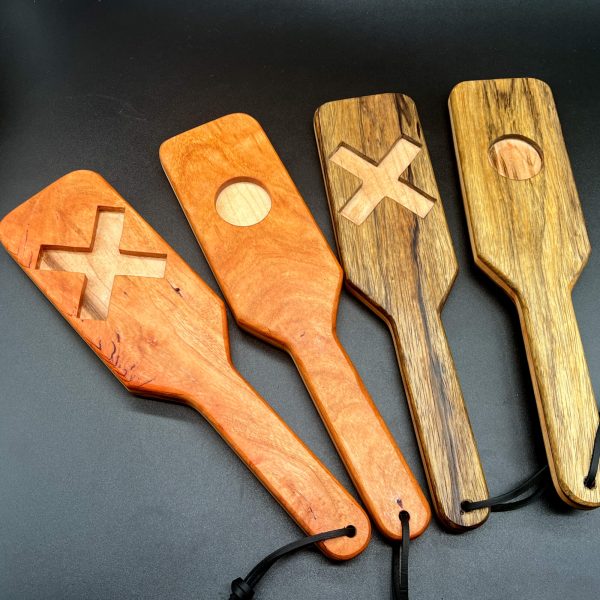 Four XOXO paddles, alternating between showing the X side and the O side. Wood types on the left - Cherry and Maple. Two wood types on the right: Black Limba and Maple