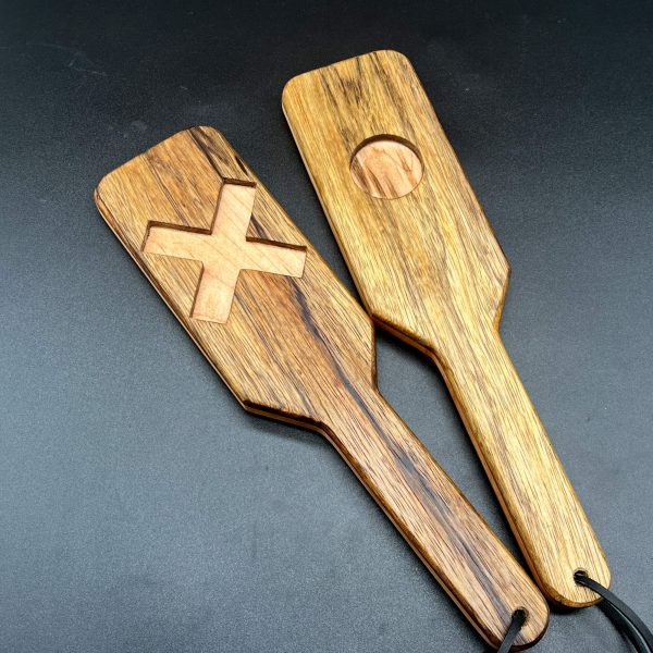 Two Black Limba and Maple XOXO paddles. The one on the left shows the X side, the one on the right shows the O side.