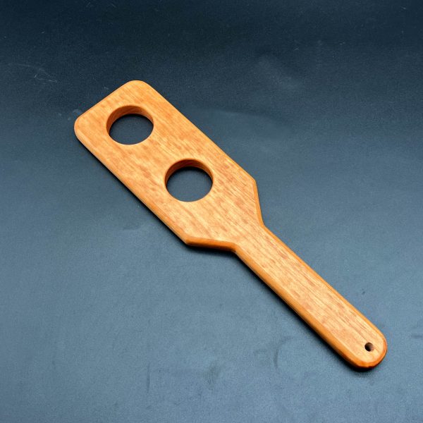 Small wooden paddle with two holes cut out of the center made from cherry wood