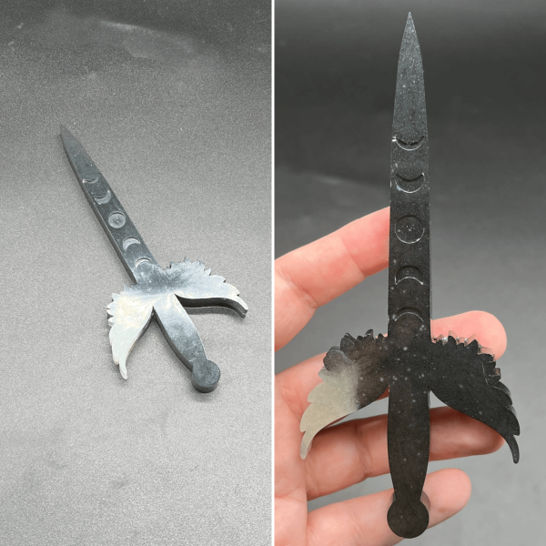 A small Poignard resin dagger made with black and white resin. The black resin is the most visible with the white resin appearing primarily in the left wing cross guard.