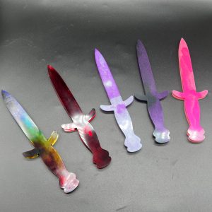 Array of current Knightly resin daggers. Left to right: Rainbow, red, purple and white, purple and black, and pink and white