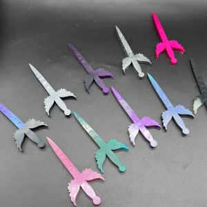 An array of small Poignard daggers. Top row, left to right: Blue color shift, silver sparkle, purple and black, gray, red and purple. Bottom row, left to right: pink and white, turquoise and red, purple and white, silver holographic, and black