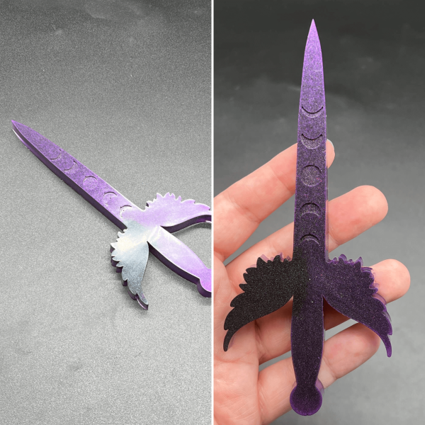 This small Poignard dagger is made with purple resin and black resin. The purple is the most visible color with black most visible in the left wing cross guard.