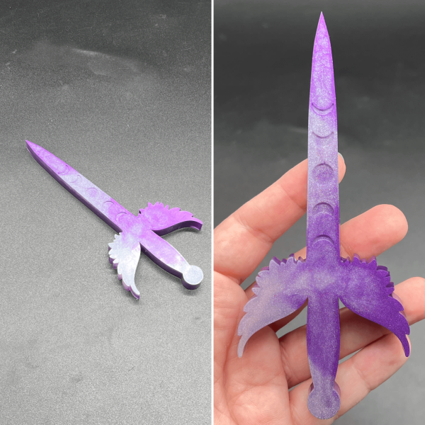 A small Poignard dagger made using purple and white resin. The purple is the most visible color. Where the white shows through, it tends to appear lilac.