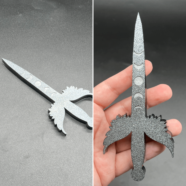 This small Poignard dagger is made with black resin and white glitter creating a silver glitter effect across the entire front of the dagger. The moon phase design is a matte silver.