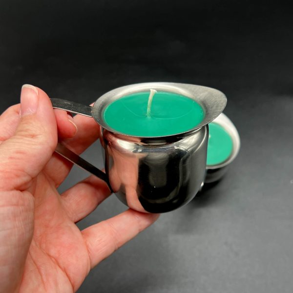 Kayla holding the 5 ounce green soy wax play candle to show the handle in use and the pour spout from the side