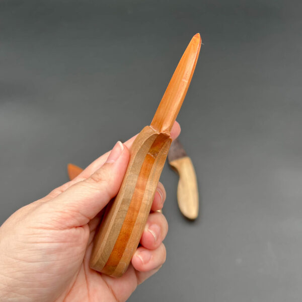 Side view of the cherry skinner wooden knife to show the handle wood on either side of the blade wood